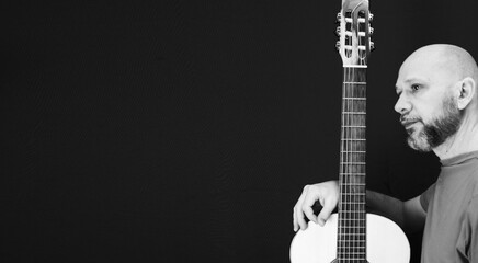 Charismatic male guitarist isolated on a dark background, grayscale shot