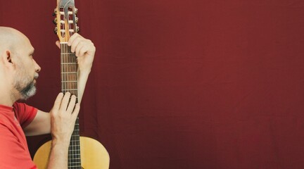 Charismatic male guitarist isolated on a red background