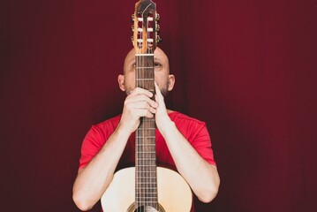 Charismatic male guitarist isolated on a red background