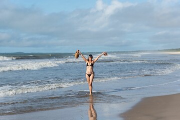Fototapeta na wymiar An adult woman in a bikini walking under strong sunlight on beac