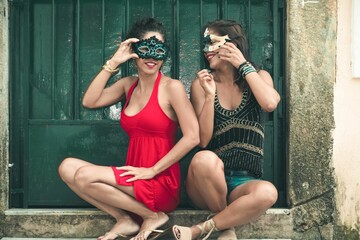 Fototapeta na wymiar Selective of two females wearing carnival masks against a door