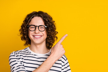Portrait of young teen guy in t shirt point finger empty space recommendation list for junior students isolated on yellow color background