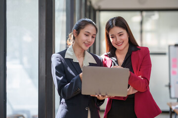 Two asian businesswomen in business attire are looking at a laptop together