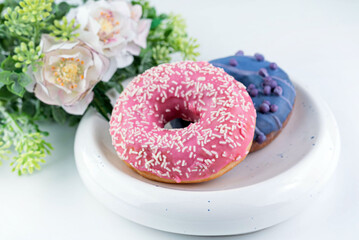 There are two donuts on a light plate on a white table.
