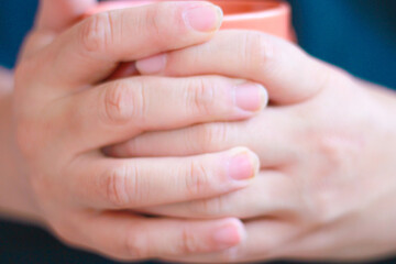 Close-up of two hands holding a cup of coffee or tea