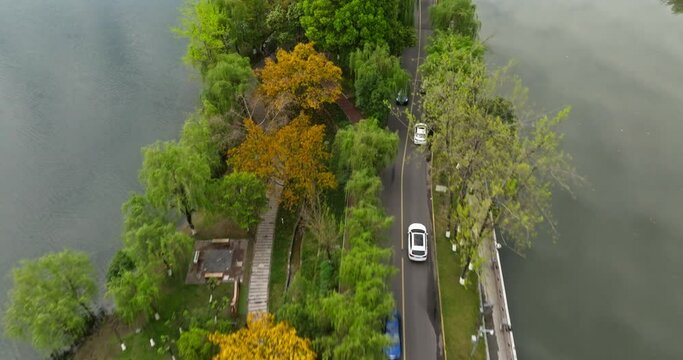 aerial view of Cars driving on the lake side road in Chengdu Donghu park, beautiful spring urban cityscape in Sichuan China
