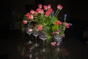 Decoration with tulips and vine glasses on the table, selective focus. Still life floral arrangement 