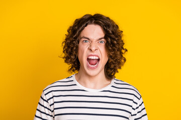 Portrait of young screaming mad furious aggressive guy wearing striped t shirt shouting open mouth...