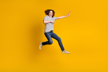 Fototapeta na wymiar Full size portrait of nice young man jump fight empty space wear striped t-shirt isolated on yellow color background