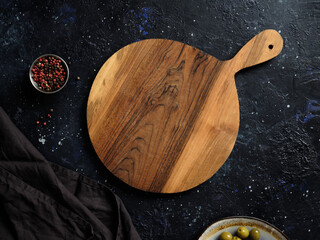 Top view of a beautiful round wooden board, decorative fabric towel, olives and spices.