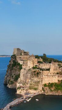 Ischia, Golfo di Napoli, Italia, l'isola con il castello Aragonese.
Vista aerea da drone, Composizione verticale, dell'isolotto di Ischia.