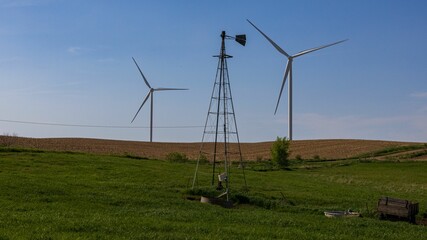 Steel structure on the grass field before the wind turbines with blue sky background