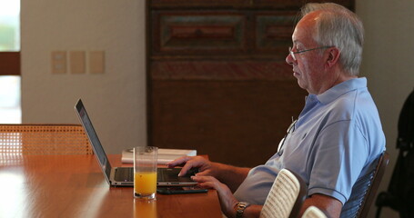 Candid older man working in front of laptop casual