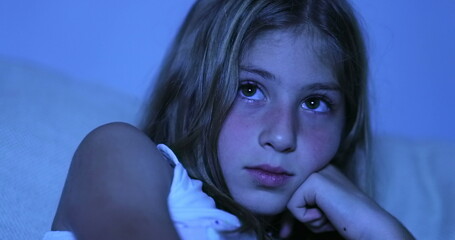 Child hypnotized by TV screen, little girl watching movie in the dark