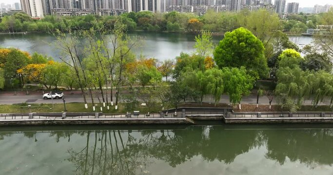 aerial view of Cars driving on the lake side road in Chengdu Donghu park, beautiful spring urban cityscape in Sichuan China