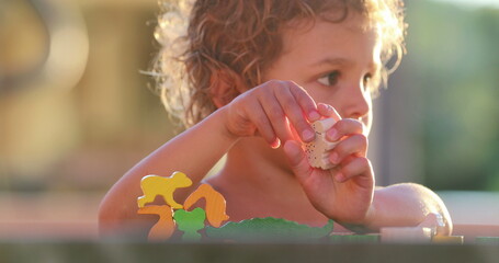 Child learning to play with puzzle pieces in deep concentration, focusing, and frustration