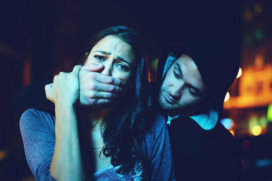 Woman, criminal and hand on mouth with terror for violence, danger and robbery in city at night with bokeh. People, portrait and silence emoji with fear, crime and gangster for kidnapping and hostage