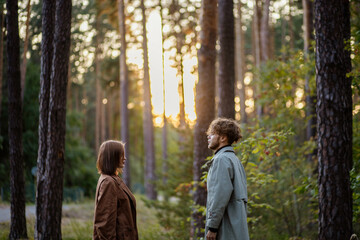 couple in love in the forest at sunset on a date hugging in a coat in the summer. Cinematic love...