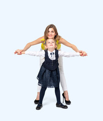 A happy young mother with her little daughter in school clothes, isolated on a light blue background
