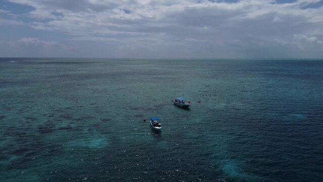 Drone shot of two boats in the middle of the blue ocean in Tulum, Mexico