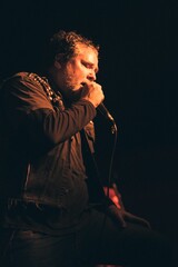 Vertical shot of a man singing into a microphone on the black background