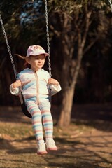 Cute caucasian young girl sitting on a swing.