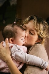 Caucasian woman holding and kissing a baby.