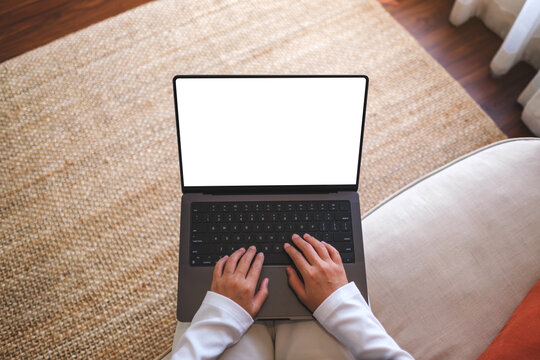 Top view mockup image of a woman working and typing on laptop computer with blank screen at home