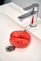 Red Rubber Human Brain under a Sink Faucet, Brainwashing Concept.