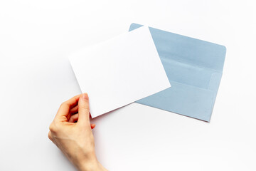 Hand holds blank paper against envelope for letters. Space for text, top view
