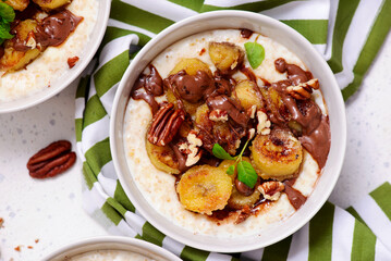 Oatmeal with caramel bananas and chocolate in to the bowl - 776042379
