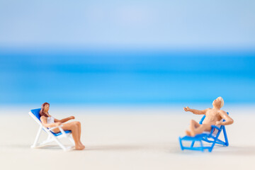 Miniature people , Couple relaxing on beach chairs on the beach