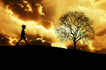 silhouette of a boy walking along a ridge at sunset