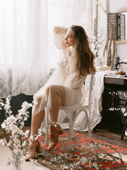 Elegant fashionable model wearing stylish vintage bridal dress sitting on chair, posing at home in vintage interior - 776057772
