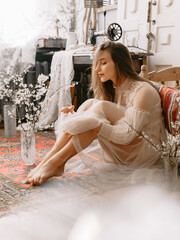 Elegant fashionable model wearing vintage bridal dress sitting on floor, posing at home, in stylish vintage interior - 776058155