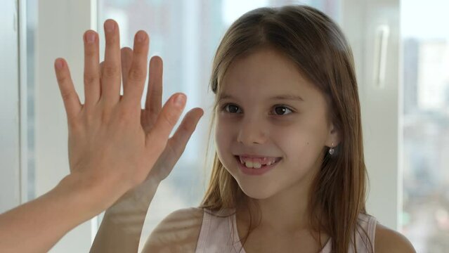Woman and child hands touching each other through glass
