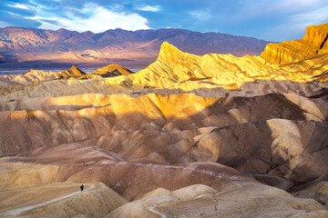 Hikers on the slopes of Zabriskie Point at sunrise in Death Valley National Park in California,...