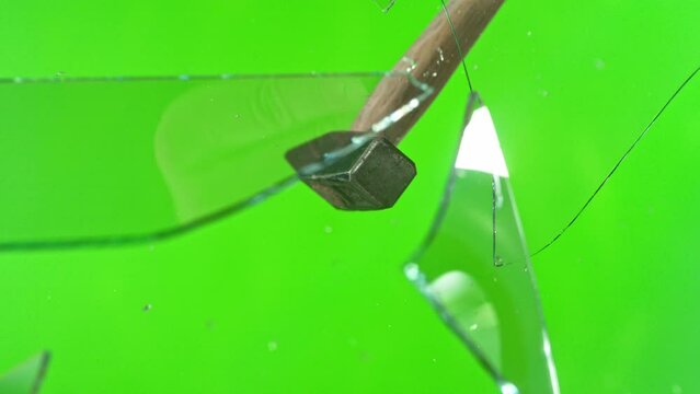 Super slow motion of glass-breaking hammer, shattering against green screen background . Filmed on high speed cinema camera, 1000 fps .