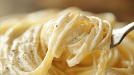 Close-up of rich, creamy Alfredo sauce with strips of fettuccine pasta twirled on a fork