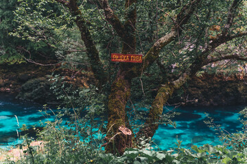 Piva River (written on the red sign) before the dam from Piva Lake was released, creating crystal clear blue watercolor, surrounded by green trees on mountains