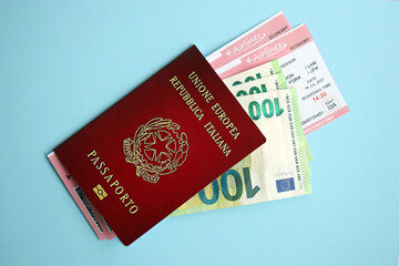 Italian passport with money and airline tickets on blue background close up. Tourism and travel concept