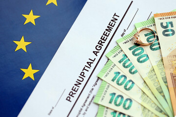 Prenuptial agreement and wedding ring on table. Premarital paperwork process in europe close up