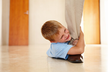 Child, happy and holding dads leg on floor for playing, bonding or family game at home. Kid, smiling and on ground pulling fathers foot for entertainment, amusement or relationship development