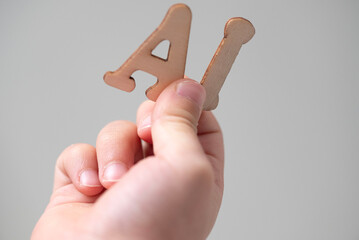 a person is holding wooden letters AI in their hand