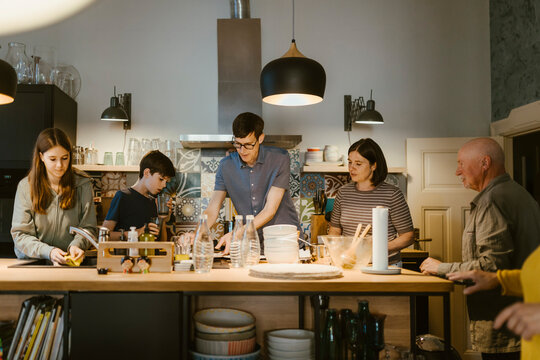 Multi-generation family helping each other in cleaning kitchen after dinner at home