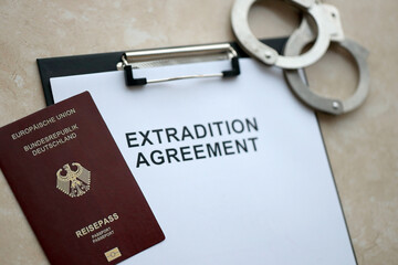 Passport of Germany and Extradition Agreement with handcuffs on table close up