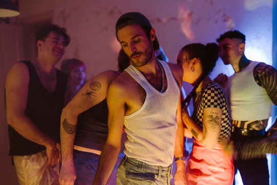 Gay person dancing with non-binary friends at nightclub