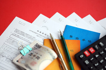 Japanese pension insurance booklets on table with yen money bills, pen and calculator on table...