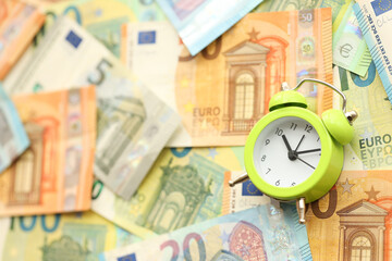 Many European euro money bills and alarm clock. Lot of banknotes of European union currency close up