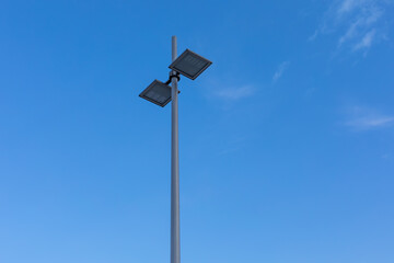A modern street lamp on a blue sky background. Double arm street light on a blue sky background